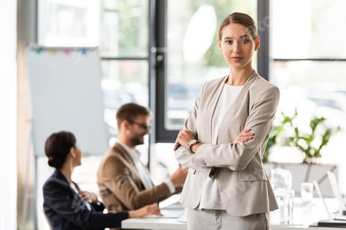 Preview: attractive businesswoman in formal wear standing with crossed arms in office