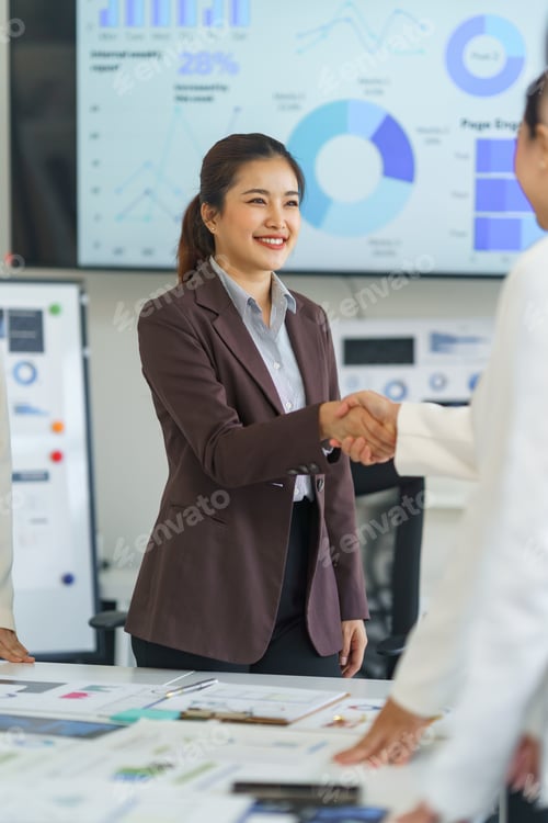 Preview: Businesswomen shaking hands after successful meeting in modern office