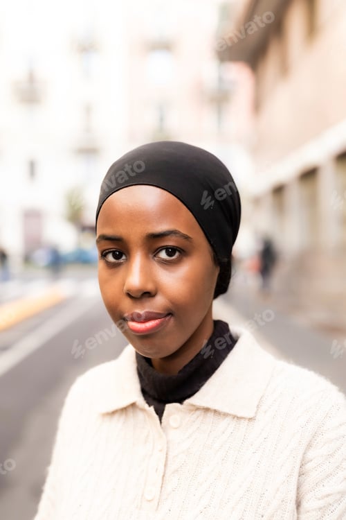 Preview: Young woman standing confidently on a city street.