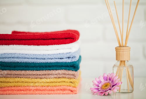 Preview: Fluffy bath towels on light wooden table with aroma sticks