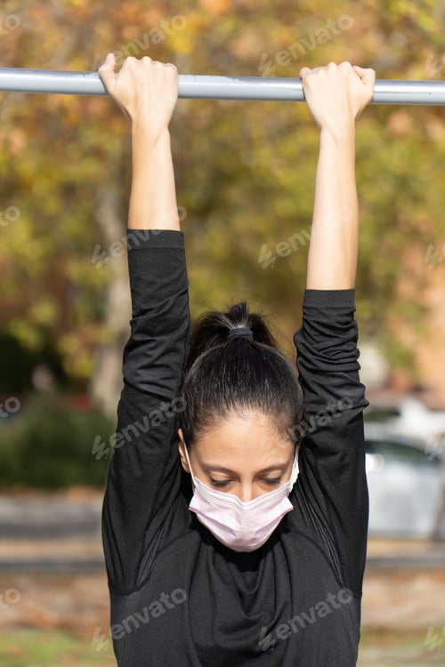 Preview: Vertical shot of a young lady exercising wearing a sanitary mask - concept of the new normal