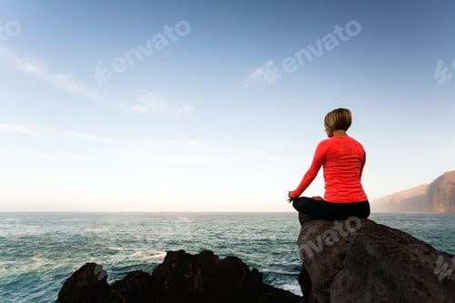 Preview: Woman meditating in yoga pose, ocean view
