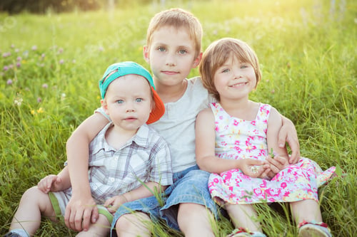 Preview: Happy children hugging sitting on the green grass outside