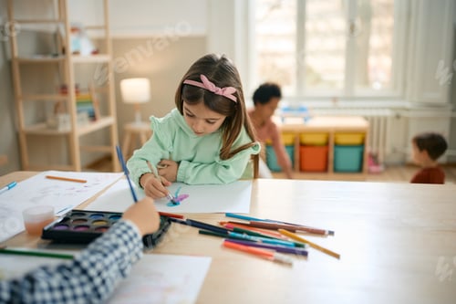 Preview: Little girl painting with watercolors during art class at preschool.