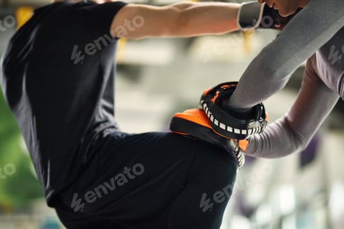 Preview: Unrecognizable fighter practicing knee kick with his instructor while working out at health club.