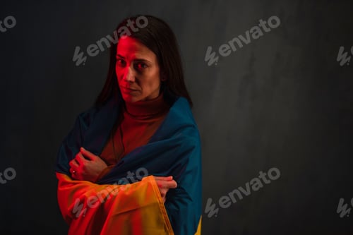 Preview: Sad woman covered with Ukraine flag. Concept of standing with Ukrainian nation in war with Russia