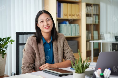 Preview: Young businesswoman sitting at her workplace