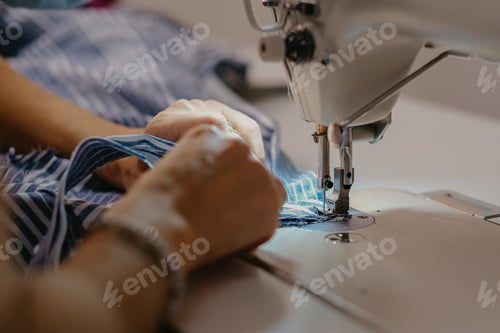 Preview: Selective focus shot of seamstress hands working on sewing machine