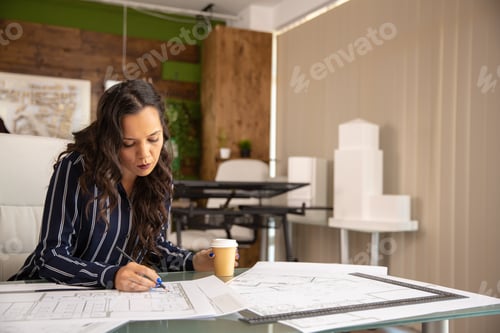 Preview: Young female architect working on blue print