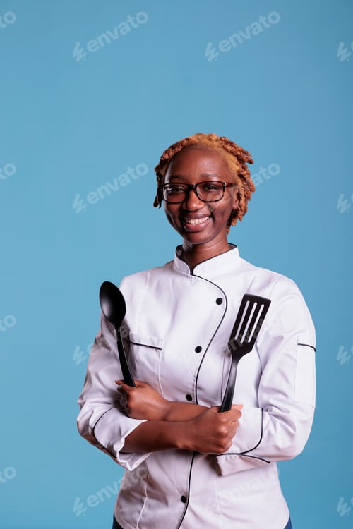 Preview: African american female head chef holding cooking utensils