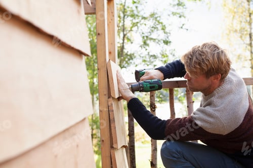 Preview: Man diligently working on a woodworking project outdoors.
