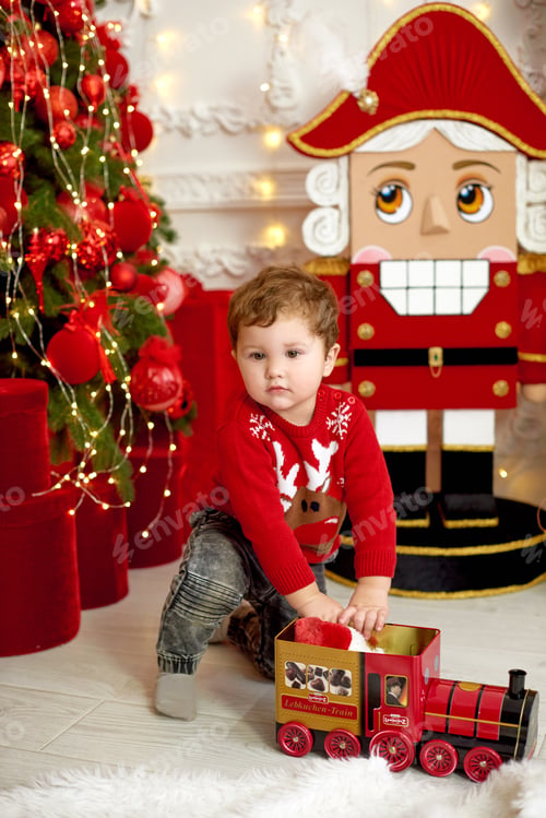 Preview: Boy play with locomotive in red style Christmas background. traditional christmas celebration