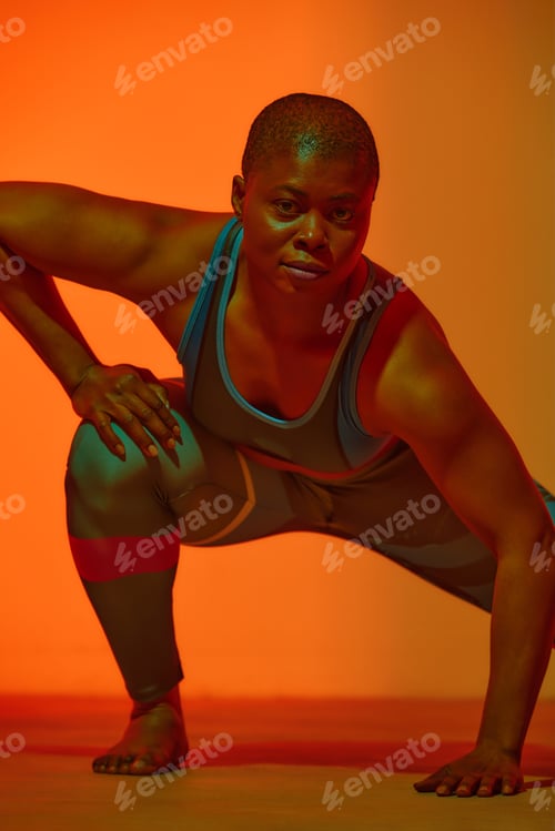 Preview: Portrait of happy young black woman in sports outfit posing and smiling on yellow studio background