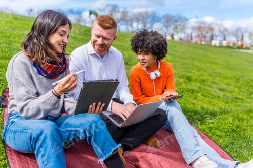 Preview: Students working with digital tablet and laptop outdoors