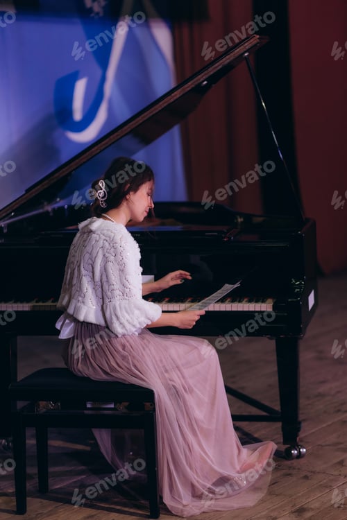 Preview: Young woman practicing piano at home and reading sheet music