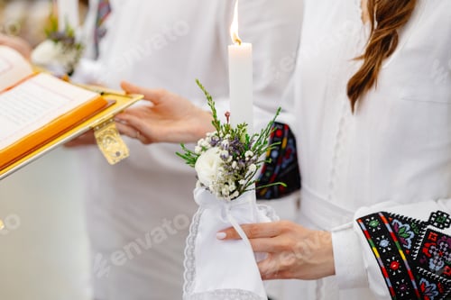 Preview: Woman holding burning candle decorated with flowers during religious ceremony