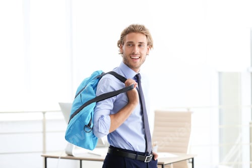 Preview: Young handsome businessman holding fitness bag in office. Gym after work