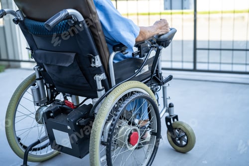 Preview: Asian senior woman patient sitting and control electric wheelchair in park at hospital.