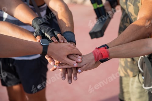 Preview: Close up on a group of hands, one on top of the other, sportspeople put their hands together