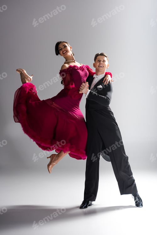 Preview: elegant young couple of ballroom dancers in red dress in suit dancing on white