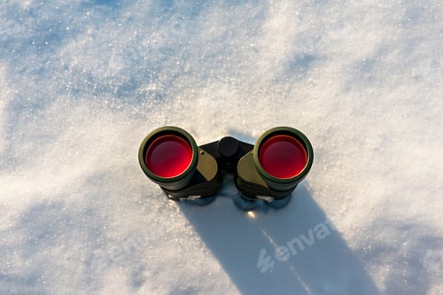 Preview: Black binoculars with red lens on white snowy winter background copy space Birdwatching ecology