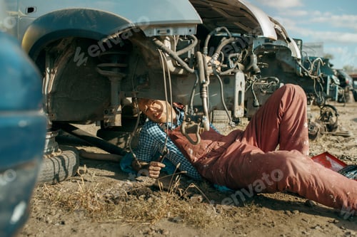 Preview: Male mechanic in welding glasses on car junkyard
