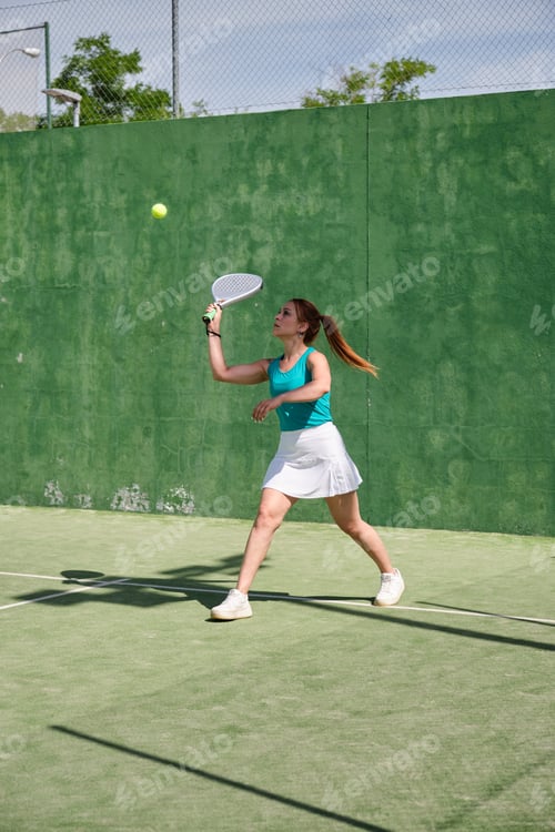 Preview: Female athlete playing paddle tennis match on sunny day