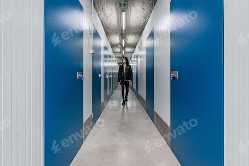 Preview: Hispanic man in a leather jacket walking in a hallway with blue doors and white walls