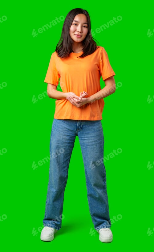 Preview: Young woman poses confidently in bright orange shirt with green background during daytime