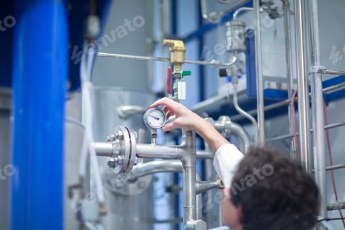 Preview: Woman with lab coat in technical room with a fermenter