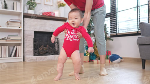 Preview: Baby learning to walk with mom in Christmas outfit during Christmas celebration at home