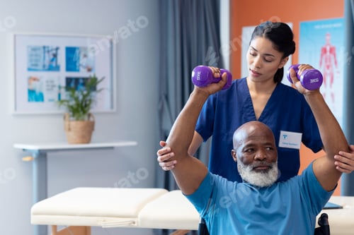 Preview: Diverse female physiotherapist helping senior male patient exercise with dumbbells, copy space