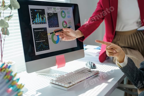 Preview: Two businesswomen discussing financial charts on a computer screen, pointing with a pen and finger t