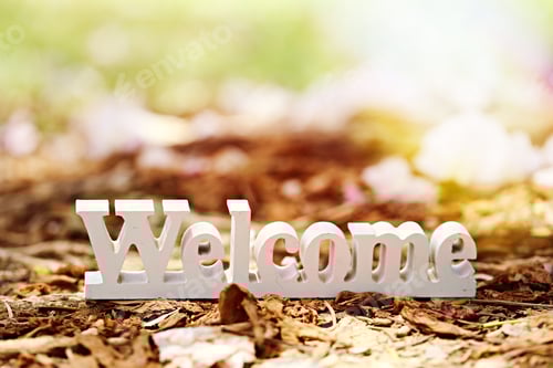 Preview: White welcome sign wooden decoration closeup on ground blur natural background.
