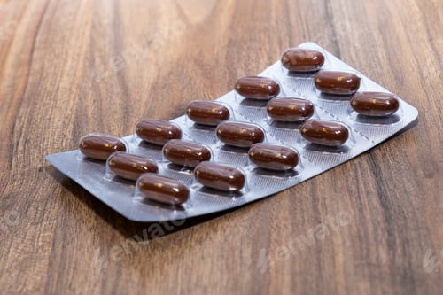 Preview: bown medical capsules pills in transparent blister pack on wooden table
