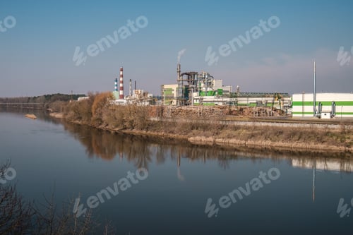 Preview: pipes of woodworking enterprise plant sawmill near river. Air pollution concept.