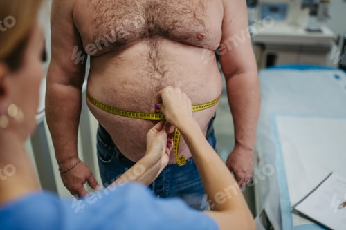 Preview: Female doctor measuring waist of overweight patient using tape measure. Obesity affecting middle