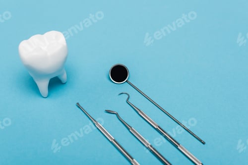Preview: High angle view of stainless dental tools and tooth model on blue background