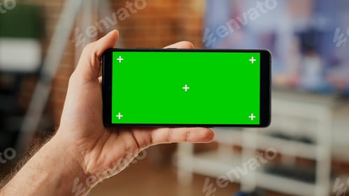 Preview: Male employee using smartphone with greenscreen display