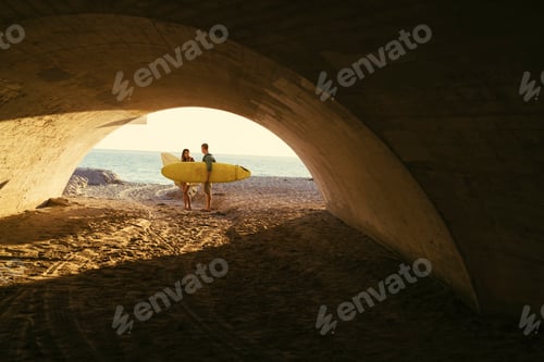 Preview: Surfing couple in underpass at Newport Beach, California, USA