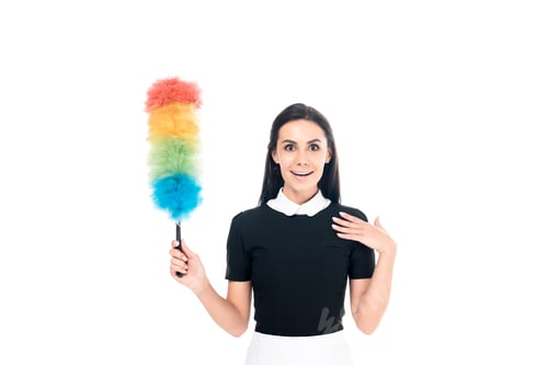 Preview: Surprised maid in uniform holding duster isolated on white