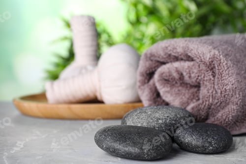 Preview: Spa stones, towel and herbal bags on grey marble table, space for text