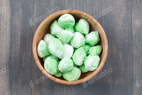 Preview: Bowl of green candies on wooden surface