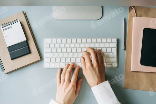 Preview: Elegant female hands typing on a computer keyboard, top view of a modern workplace.