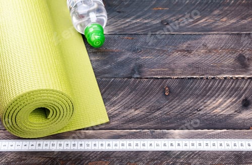 Preview: Yoga mat, water bottle and centimeter on a wooden background. Equipment for yoga