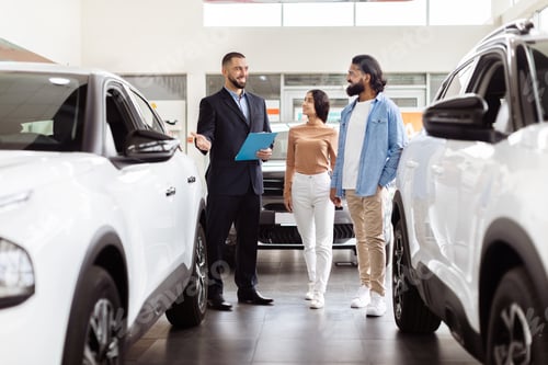 Preview: Professional Salesman Introducing New Car Models to Couple at Showroom