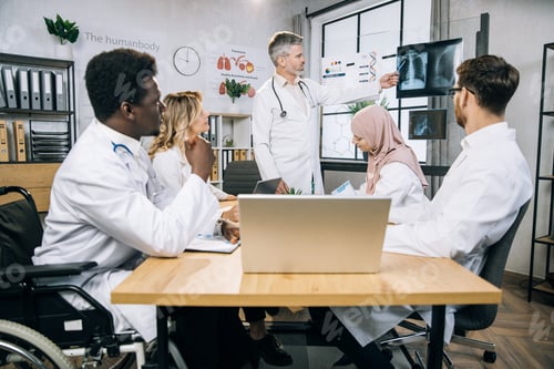 Preview: Mature doctor talking about x ray scan to diverse colleagues