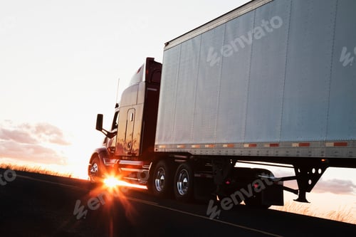 Preview: Silhouette of a commercial truck driving on a highway at sunset.