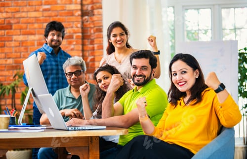 Preview: Young Indian entrepreneurs cheerfully celebrating success at a startup office after hard work
