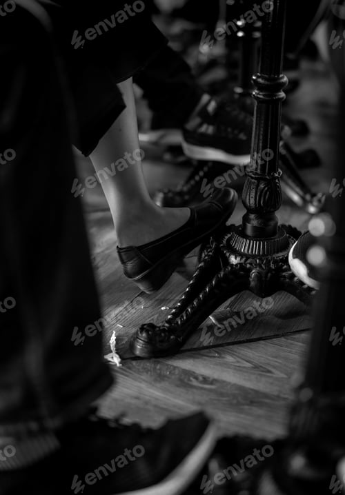 Preview: Closeup legs of a man and a woman under the table at coffee shop. Vintage style table in restaurant.